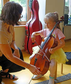 Eine miusikschullehrerin unterweist ein Mädchen am Violoncello