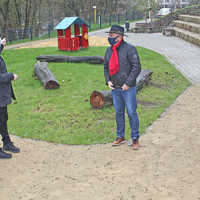 Mitarbeiter von StadtRaum und Jugendamt besichtigen gemeinsam mit dem Ortsvorsteher Hanspitt Weiler den neuen Spielplatz in Heiligkreuz. Im Hintergrund steht ein rotes Spielhäuschen.