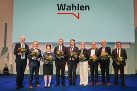 Neun Personen, darunter Oberbürgermeister Wolfram Leibe, stehen mit Blumenstrauß auf einer Bühne und lächeln in die Kamera.