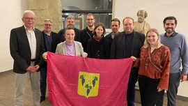 Bürgermeisterin Elvira Garbes, Vertreter der Stadtratsfraktionen und Mitglieder der Deutsch-Ukrainischen Gesellschaft präsentieren die Fahne der neuen Partnerstadt Isjum. 