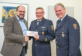 Dezernent Thomas Egger (links) und Feuerwehrchef Herbert Albers-Hain (rechts) schenkten Olaf Backes für seine 35-jährige ehrenamtliche Tätigkeit bei der Freiwilligen Feuerwehr Biewer einen Gutschein für eine Grill-Akademie.