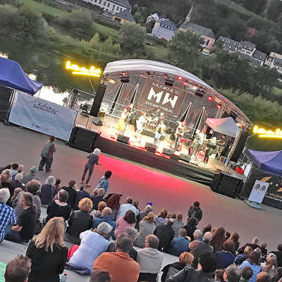 Beim Kulturhafen am Zurlaubener Moselufer können die Besucher neben Live-Musik an lauen Sommerabenden den Ausblick auf den Fluss und die roten Felsen in Pallien genießen. 