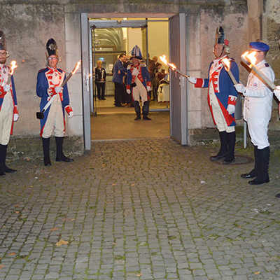 Die Stadtgarde Augusta Treverorum erwartet mit einem eindrucksvollen Fackelspalier auf dem Hof beim Eingang zum Rathaussaal die Gäste der Jubiläumsfeier. In den eindrucksvollen blau-roten Uniformen, den ältesten Wappenfarben der Stadt Trier, ziehen die verschiedenen Corps kurz danach in den historischen Saal ein. Foto: Seng