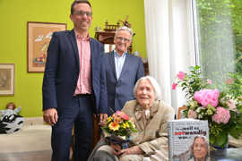 Beigeordneter Thomas Schmitt (l.) und der Heiligkreuzer Ortsvorsteher Theodor Wolber gratulieren Liesel Hünichen zu ihrem 100. Geburtstag. Die Jubilarin hat zahlreiche Bücher verfasst.