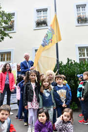 OB Wolfram Leibe steht mit vielen Kindern vor dem Fahnenmast an dem die Kinderrechtsflagge gehisst wird.