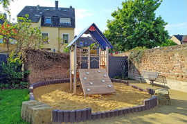 Ein Spielplatz mit einer überdachten Kletterstation, die auf einem Sandboden steht.