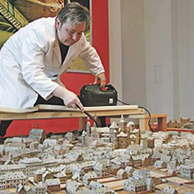 Restaurator Dimitri Bartashevich reinigt den Dom des Stadtmodells mit einem Spezialstaubsauger.