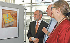 Rudolf Hahn, Chef des Bildungs- und Medienzentrums (Mitte), erläutert OB Jensen und Bürgermeisterin Angelika Birk ein Exponat der Ausstellung „ÜberLeben ohne Schrift“.