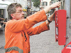 Hubert Holstein, Mitarbeiter der Stadtreinigung, befestigt einen der Tütenspender in der Glockenstraße.