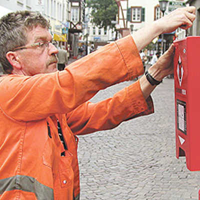Hubert Holstein, Mitarbeiter der Stadtreinigung, befestigt einen der Tütenspender in der Glockenstraße.