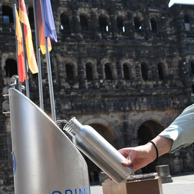 Vor der Porta Nigra wird an einem Wasserspender eine Trinkflasche gefüllt