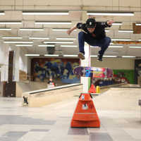 Ein Skater und sein Board befinden sich in der Luft bei einem Trick an einem Rail