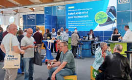 Besucher einer Messe lassen sich an einem Infostand beraten