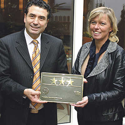 Beigeordnete Christiane Horsch überreicht Hotelier Wahid Driss die Drei-Sterne-Plakette für das Primavera.