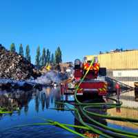 Ein großer Schrotthaufen und ein Löschwagen, davor ein riesiger See mit Löschwasser