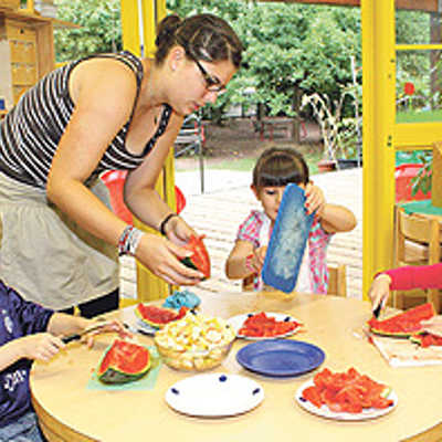 Kinder aus der blauen Gruppe im Montessori-Kinderhaus St. Peter schneiden mit Betreuerin Lena Schischke Obst für das Frühstücksmüsli.