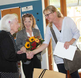 Bürgermeisterin Elvira Garbes und Regina Bruhn gratulieren Justine Vicari mit einem Blumenstrauß in den Trierer Stadtfarben zum 100. Geburtstag.