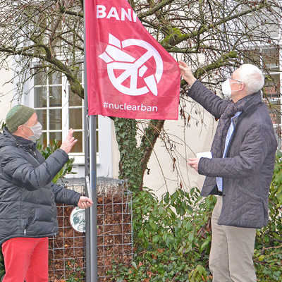 OB Wolfram Leibe (r.) hisst mit Unterstützung von Alois Barra die Flagge der Internationalen Kampagne zum Verbot von Atomwaffen (ICAN) vor dem Rathaus.