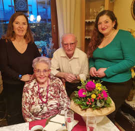 Elvira Garbes und Hasmik Garanian stehen mit den Jubilaren Rosa Maria und Wendelinus Deutsch an der festlich gedecken und mit Blumen geschmückten Kaffeetafel. 