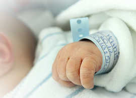 Neugeborenes Baby mit Namensbändchen.