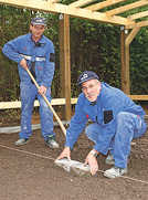 Die Stadtwerke-Mitarbeiter Elmar Herold und Karl-Heinz Maes bereiten die Pflasterarbeiten auf dem Boden des Freiluft-Klassenraums vor. Foto: SWT