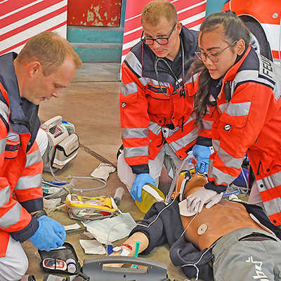 Die Notfallsanitäter Dieter Wittich und Christian Jakobs demonstrieren mit Rettungssanitäterin Thuy Hoang (v. l.) an einer Puppe die notfallmedizinische Erstversorgung eines nicht ansprechbaren Patienten.