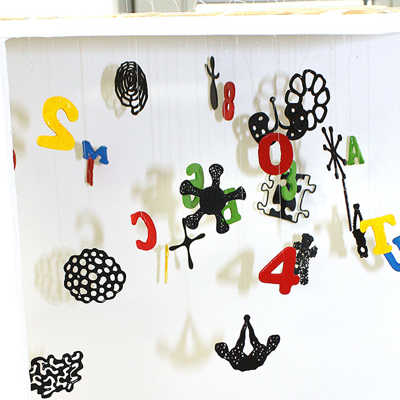 Die Installation von Bodo Korsig kombiniert Zahlen und Buchstaben mit schwarzen Objekten in organischen Formen.