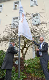 OB Wolfram Leibe (r.) hisst gemeinsam mit Uni-Präsident Professor Michael Jäckel die Flaggen vor dem Rathaus. Die Universität Trier feiert in diesem Jahr ihr 50-jähriges Bestehen.