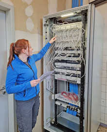 Elektrikerin Maren Michel prüft einen Serverschrank in der Grundschule St. Matthias. Zu dem dortigen Sanierungsprojekt gehörte auch das Verlegen der blauen Netzwerkkabel.