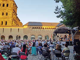 Besucherinnen und Besucher sitzen vor einer Konzertbühne in einem historischen Innenhof