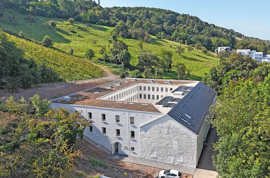 Das sanierte und erweiterte frühere Ökonomiegebäude des Klosters, ein kalkweiß verputztes Geviert mit Flachdach, wurde am Fuß des Petrisbergs in den Hang gebaut.