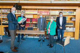Adolf Welter steht mit seiner Frau und Vertretern der Stadt und des Stadtarchivs vor einer Bücherwand.
