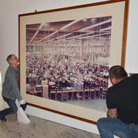 Restaurator Stefan Schu und Haustechniker Franz Meyer hantieren mit einer großformatigen Fotografie von Andreas Gursky für die Ausstellung "Lebenswert Arbeit" im Museum am Dom. 