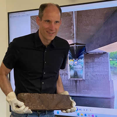 Baudezernent Dr. Thilo Becker mit einem Bruchstück des defekten Brückenlagers aus Edelstahl. 