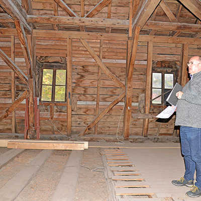Projektleiter Jürgen Eckstein erläutert im Obergeschoss des geschlossenen Exhaus-Mittelteils, dass dort zahlreiche Holzbalken vom sogenannten Hausschwamm befallen sind.