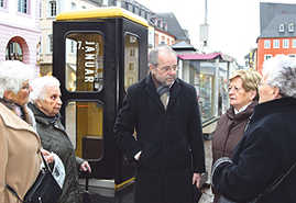 OB Klaus Jensen im Gespräch mit vier Triererinnen, die ihre Erinnerungen zu der Zeitzeugenaktion beigetragen haben. Im Hintergrund die Telefonzelle, in der die Mitschnitte angehört werden können.