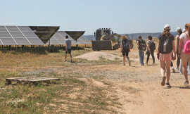 Eine Besucherinnengruppe besichtigt Photovoltaikmodule auf einer Freifläche