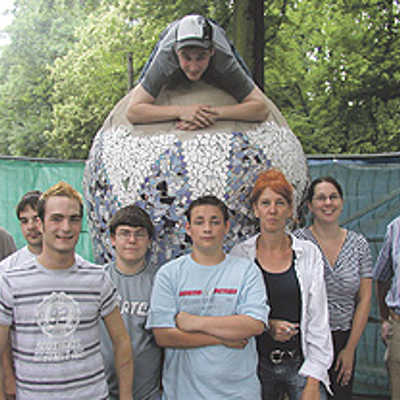 Gemeinsam mit den Jugendlichen freuen sich Gerrit Rohlfs (v. l.) vom städtischen Grünflächenamt, Sozialpädagogin Maren Zollikofer und Künstlerin Nadja Selting über die fast fertige Skulptur im Park Nells Ländchen.