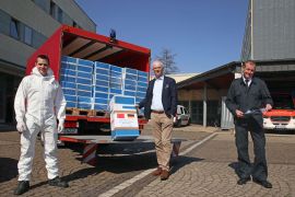 OB Leibe (Mitte) und Feuerwehrchef Andreas Kirchartz (rechts) nehmen die Schutzanzüge in Empfang. Links ein Feuerwehrmann im Schutzanzug. OB Leibe (Mitte) und Feuerwehrchef Andreas Kirchartz (rechts) nehmen die Schutzanzüge in Empfang. Links ein Feuerwehrmann im Schutzanzug.