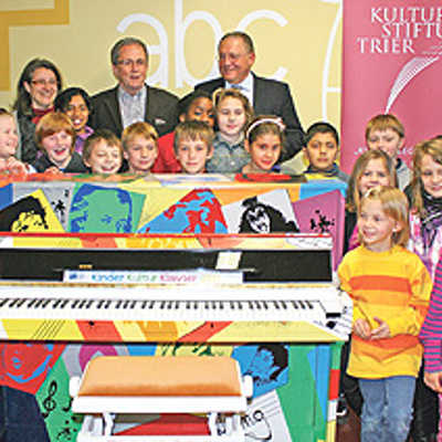 Die Matthias-Grundschüler und Rektorin Christina Steinmetz (hinten  l.) über das außergewöhnliche Klavier. Foto: Agenturhaus