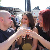 André Seibel, Katharina Rosner und Anja Fassbender prosten sich bei strahlendem Sonnenschein mit einem Marx-Bier zu. 