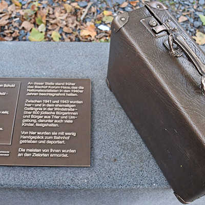 Seit Oktober 2020 erinnert an der Ecke Rindertanzplatz/Sichelstraße in der Innenstadt ein Reisekoffer aus Bronze an die Juden-Deportationen 1941. Auf der Tafel daneben steht neben einem Info-Text ein Gedicht der aus Trier stammenden jüdischen Dichterin Gerty Spies.