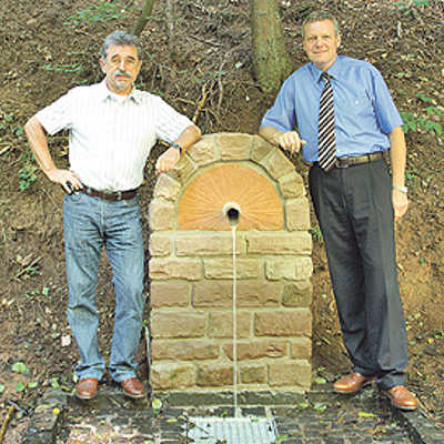 Stadtwerke-Vorstand Olaf Hornfeck (rechts) und Friedel Jaeger präsentieren den erneuerten Brunnen. Foto: SWT