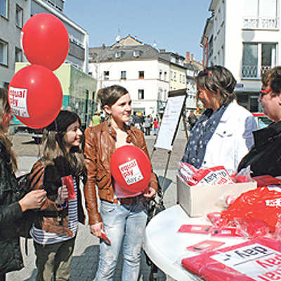 AMG-Schülerinnen nehmen sich nach dem Gespräch mit Frauenbeauftragter Angelika Winter (Mitte) und Martina Ackermann von ver.di (r.) die beliebten roten Luftballons der Gleichstellungskampagne mit.