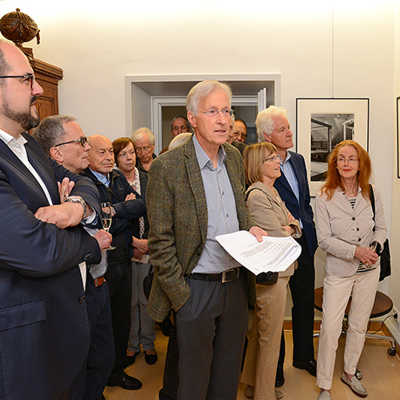 Bei der Vernissage im Trier-Zimmer des Rathauses erläutert Dr. Johannes Henke (Mitte) den zahlreichen Gästen die Motive seiner Fotoausstellung.