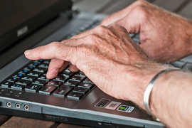 Hände eines älteren Users auf einer tastatur.