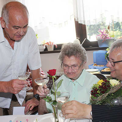 Ortsvorsteher Bernd Michels (links) und Baudezernent Andreas Ludwig stoßen mit Maria Willems mit einem Glas Sekt an. 