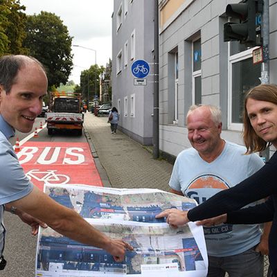 Verkehrsdezernent Dr. Thilo Becker (l.) und Verkehrsplaner Jonas Klöpfer (r.) tauschen sich mit Bauleiter Georg Gulla (Mitte) über den Fortschritt der Markierungsarbeiten für die neue Umweltspur in der Südallee aus.