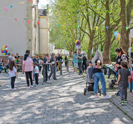 Straßenfest unter Bäumen mit Luftballons, Kindern ud Erwachsenen