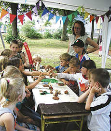 Kinder mit Betreuerin an enem Tisch